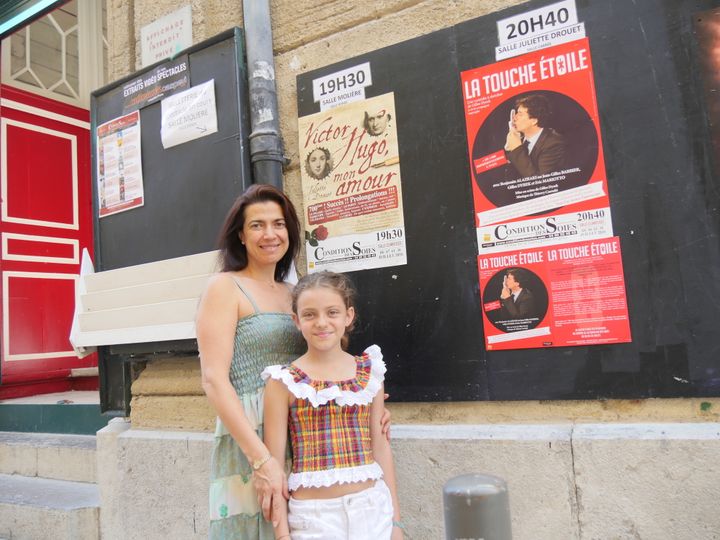 Anthéa Sogno avec sa fille Théodora en face du théatre La Condition des soies le 6 juillet, avec l'affiche du specatacle "Victor Hugo mon amour".
 (LCA/Culturebox)