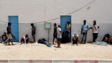 Après avoir été secourues en mer, des personnes attendent devant un bâtiment de Médenine, dans le sud-est de la Tunisie, le 7 juillet 2021. (TASNIM NASRI / ANADOLU AGENCY / AFP)