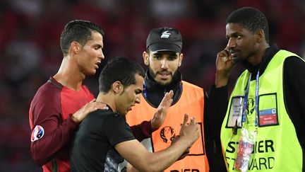 Un supporter tente de prendre un selfie avec Cristiano Ronaldo, après s'être invité sur la pelouse du Parc des Princes, samedi 18 juin 2016, au terme de la rencontre entre le Portugal et l'Autriche (0-0). (FRANCISCO LEONG / AFP)