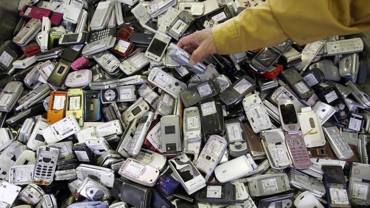 Un ouvrier d'une usine de recyclage de Tokyo (Japon) saisit un t&eacute;l&eacute;phone portable au milieu de vieux mobiles. (TORU HANAI / REUTERS)