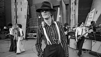 David Bowie à Los Angeles en septembre 1974, durant les répétitions de la seconde partie de son Diamond Dogs Tour, baptisé aussi The Soul/Philly/Dogs Tour.  Le musicien Earl Slick est au second plan, 3e en partant de la droite.
 (Terry o&#039;Neill / Getty Images)