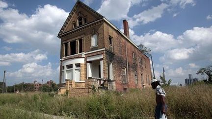 Un homme en train de marcher près d'une maison abandonnée dans un quartier autrefois animé situé près du centre-ville de Detroit (Michigan), le 19 juillet 2013. (Reuters - Rebecca Cook)