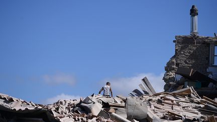 Un homme au sommet d'une ruine &agrave; Amatrice&nbsp;le 24 ao&ucirc;t (FILIPPO MONTEFORTE / AFP)