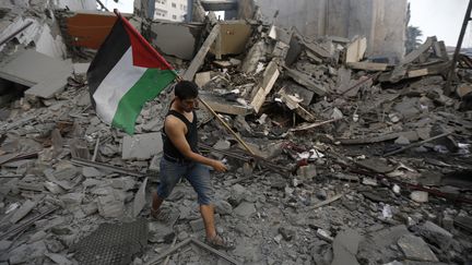 Un habitant de la bande de Gaza sort un drapeau palestinien des d&eacute;combres, apr&egrave;s une frappe isra&eacute;lienne sur Gaza, le 26 ao&ucirc;t 2014. (MOHAMMED ABED / AFP)