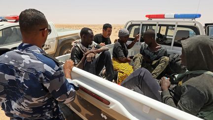 Des garde-frontières libyens portent secours à des migrants dans le désert à la frontière avec la Tunisie, dimanche 16 juillet 2023, près d'Al Assah. (MAHMUD TURKIA / AFP)