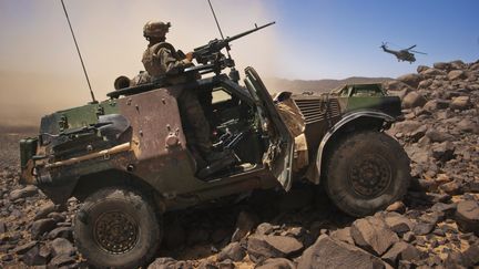 Un soldat fran&ccedil;ais monte la garde &agrave; bord d'un v&eacute;hicule blind&eacute;, alors qu'un h&eacute;licopt&egrave;re d&eacute;colle dans la vall&eacute;e de Terz (nord du Mali), le 21 mars 2013. (FRANCOIS RIHOUAY / REUTERS)