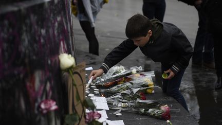 Un enfant allume une bougie, place de la République. (MARTIN BUREAU / AFP)