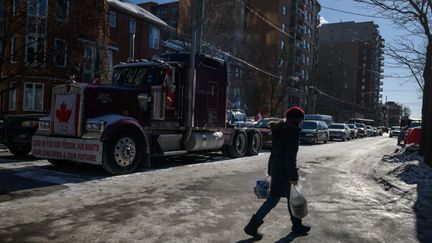 Une femme passe devant un camion qui bloque une rue d'Ottawa pour protester contre les mesures sanitaires prises au Canada, le 14 février 2022. (ED JONES / AFP)