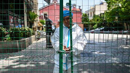 Un homme ferme le portail d'une résidence, à Shanghai (Chine), le 8 juin 2022.&nbsp; (HECTOR RETAMAL / AFP)