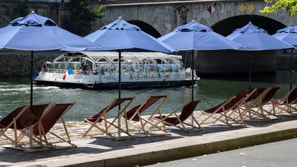 Un bateau de touristes passant devant des transats vides le long de la Seine lors de Paris plage à Paris,  le 13 juillet 2022. (BERTRAND GUAY / AFP)