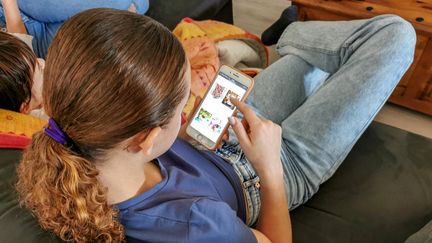 Une adolescente consulte son téléphone à Valence (Drôme), le 26 décembre 2021. (NICOLAS GUYONNET / HANS LUCAS / AFP)