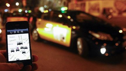 L'application Uber sur un smartphone devant un taxi à Barcelone (Espagne),le 9 décembre 2014. (AFP - QUIQUE GARCIA)