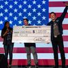 Le milliardaire Elon Musk remet un chèque d'un million de dollars à une signataire de sa pétition, le 28 octobre 2024 à Lancaster, en Pennsylvanie (Etats-Unis). (SAMUEL CORUM / GETTY IMAGES NORTH AMERICA / AFP)