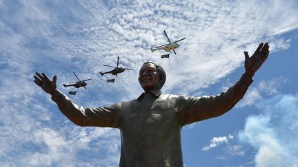 Des h&eacute;licopt&egrave;res transportant le drapeau sud-africain volent au-dessus de la statue r&eacute;cemment d&eacute;voil&eacute;e de l'ancien pr&eacute;sident Nelson Mandela &agrave; Pretoria (Afrique du sud), le 16 d&eacute;cembre 2013. (ALEXANDER JOE / AFP)