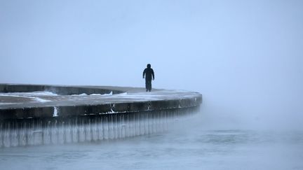 Un homme marche dans le brouillard au bord du lac Michigan, à Chicago (Illinois), le 22 décembre 2022. (SCOTT OLSON / GETTY IMAGES NORTH AMERICA / AFP)