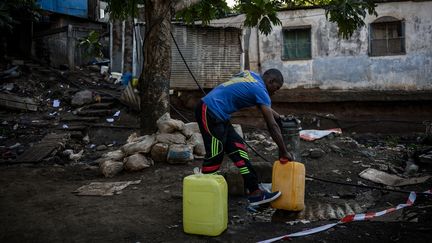 Un homme remplit des bidons d'eau à Koungou (Mayotte), le 23 mai 2023. (PHILIPPE LOPEZ / AFP)