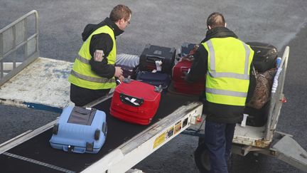 Des employ&eacute;s a&eacute;roportuaires chargent des bagages en soute, le 27 janvier 2014, &agrave; Beauvais (Oise). (PHILIPPE TURPIN / PHOTONONSTOP / AFP)