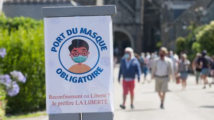 Un panneau qui indique que le port du masque est obligatoire&nbsp;à l'extérieur dans le centre de Locronan en Bretagne, le 3 août 2020.&nbsp; (QUEMENER YVES-MARIE / MAXPPP)