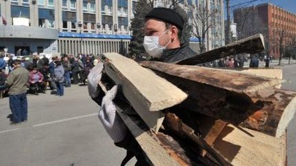 Un manifestant pro-russe apporte du bois pour renforcer une barricade érigée devant le bâtiment des services de sécurité dans la ville ukrainienne de Lugansk, le 8 avril 2014.  (AFP PHOTO / GENYA SAVILOV)