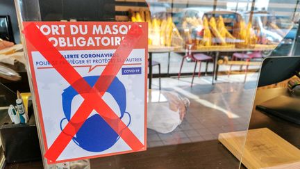 A Valence (Drôme), une affiche dans une boulangerie rappelle que le port du masque n'est plus obligatoire&nbsp;dans les commerces depuis le lundi 14 mars 2022. (NICOLAS GUYONNET / HANS LUCAS / AFP)