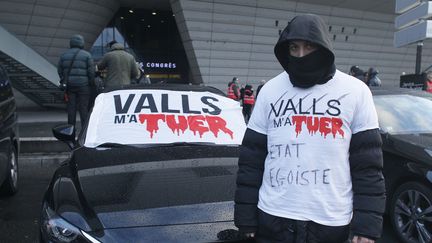 "Valls m'a tué-Etat Egoïste." Un chauffeur de VTC manifeste contre le gouvernement à la porte Maillot, à Paris, le 11 février 2016. (MATTHIEU ALEXANDRE / AFP)