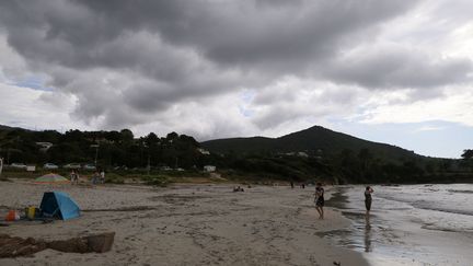 Des baigneurs sur la plage de&nbsp;Mare e Sole, alors qu'un orage approche, le 14 juin 2018. (PASCAL POCHARD-CASABIANCA / AFP)