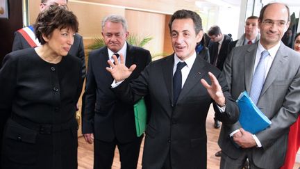 Alors pr&eacute;sident de la R&eacute;publique, Nicolas Sarkozy s'entretient avec des employ&eacute;s de la Direction D&eacute;partementale de la Coh&eacute;sion Sociale (DDCS) de Laon, aux c&ocirc;t&eacute;s de son&nbsp;ministre du Budget,&nbsp;Eric Woerth, le 02 mars 2010. (FRANCOIS NASCIMBENI /AFP)