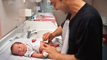 Un père change son enfant peu après sa naissance à l'hôpital franco-britannique de Levallois-Perret.&nbsp; (DIDIER PALLAGES / AFP)