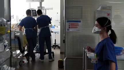 Des soignants prennent en charge un malade du Covid-19 dans le service de soins intensifs de l'hôpital Ambroise Paré de&nbsp;Boulogne-Billancourt (Hauts-de-Seine), en mars 2021. (ALAIN JOCARD / AFP)