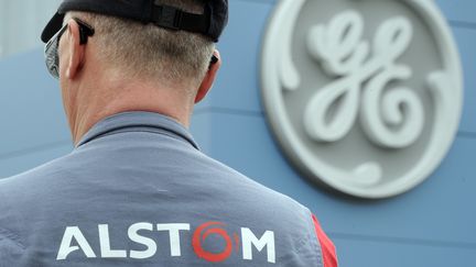 Un employ&eacute; d'Alstom devant un logo de General Electric, le 29 avril 2014, &agrave; Belfort. (SEBASTIEN BOZON / AFP)