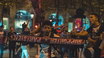 Des supporters du PSG fêtent la qualification du club pour la finale de la Ligue des champions sur les Champs-Elysées à Paris, le 18 août 2020. (BENJAMIN GUILLOT-MOUEIX / AFP)