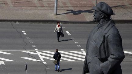  (En Ukraine, la décommunisation passe aussi par le changement de nom des rues [Image d'illustration : à Kiev, des passants traversent la rue près d'une statue de Lénine] ©  REUTERS/Marko Djurica)