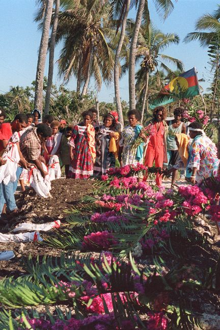 Des personnes se recueillent devant les sépultures de militants indépendantistes tués pendant l'assaut de la grotte, le 8 mai 1988 à Ouvéa. (REMY MOYEN / AFP)