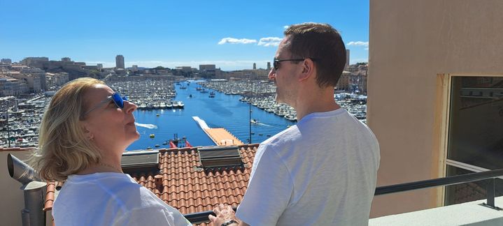 Nelly et Alain profitent de leur balcon avec vue sur le Vieux Port de Marseille qu'ils ont réservé un an avant l'arrivée de la flamme, le 8 mai 2024. (RAPHAEL GODET / FRANCEINFO)