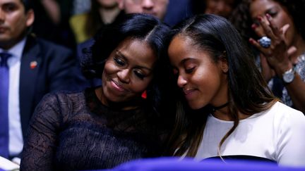 La première dame des Etats-Unis, Michelle Obama, et sa fille, Malia, s'embrassent en écoutant la déclaration d'amour de Barack Obama, le 10 janvier 2017, à Chicago (Illinois).&nbsp; (JONATHAN ERNST / REUTERS)