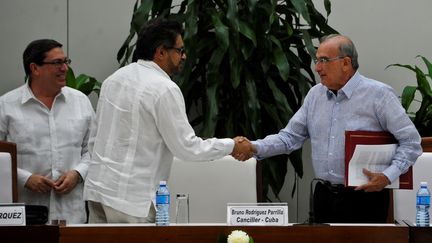 Le responsable des Farc Ivan Marquez (au centre) serre la main du délégué&nbsp;du gouvernement colombien chargé des accords de paix Humberto de la Calle (à droite), samedi 12 novembre 2016 à La Havance (Cuba). (YAMIL LAGE / AFP)