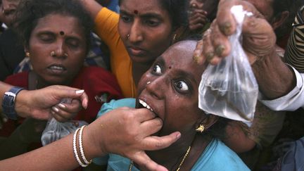 Une femme avale un poisson vivant pour soigner ses probl&egrave;mes respiratoires &agrave; Hyderabad (Inde), le 8 juin 2012. (KRISHNENDU HALDER / REUTERS)