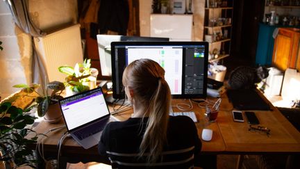 Une femme installée dans son salon travaille à distance, à Angers (Maine-et-Loire), le 30 mars 2020. (THIBAUD VAERMAN / HANS LUCAS / AFP)