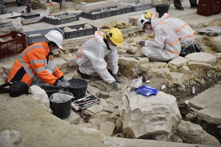 Les archéologues de l'INRAP sortent le jubé de terre, le 15 mars 2022. (JULIEN DE ROSA / AFP)