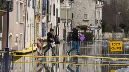 Des habitants de Tournus (Saône-et-Loire) traversent une rue inondée par la crue de la Saône, le 29 janvier 2018. (PHILIPPE DESMAZES / AFP)