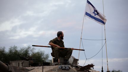 Un soldat israélien est assis sur un char stationné près de la frontière nord d'Israël avec le Liban, le 30 octobre 2023. (JALAA MAREY / AFP)