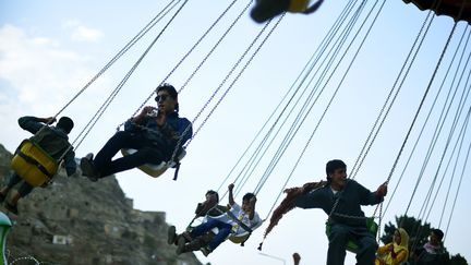 Des jeunes Afghans s'amusent dans un manège à l'occasion des vacances de l'Eid al-Fitr, à Kaboul, le 17 juillet 2015. (WAKIL KOHSAR / AFP)