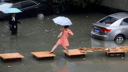 Une femme tente de se d&eacute;placer sur un pont de fortune apr&egrave;s que de violents orages ont inond&eacute; la ville de Wuhan (Chine), le 29 mai 2012. (AFP)