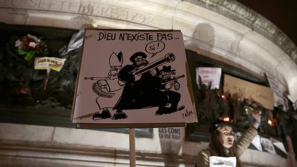 Un manifestant brandit une caricature dessin&eacute;e par Cabu, tu&eacute; lors de l'attaque de "Charlie Hebdo",&nbsp;lors du rassemblement du 7 janvier 2015, place de la R&eacute;publique, &agrave; Paris.&nbsp; (JOEL SAGET / AFP)