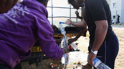 Des migrants lors d'une distribution d'eau, en juin 2017, à Calais. (OLIVIER ARANDEL / MAXPPP)