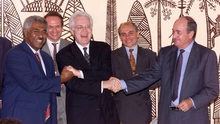 Le Premier ministre Lionel Jospin, entouré de Roch Wamytan, leader des indépendantistes néo-calédoniens, et de Jacques Lafleur, dirigeant loyaliste, lors de la signature de l'accord de Nouméa, le 5 mai 1998. (PASCAL GUYOT / AFP)