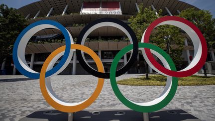 Les anneaux olympiques se sentiront bien seuls ce vendredi 23 juillet, devant le stade olympique de Tokyo, où la cérémonie d'ouverture ne sera vue que par 950 spectateurs en tribunes... mais des centaines de millions à la télévision. (BEHROUZ MEHRI / AFP)