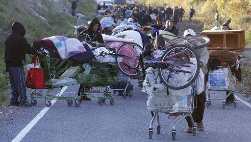 Familles roms poussant des caddies de supermarché remplis avec leurs affaires après avoir été expulsés d'un campement à Nice le 27 novembre 2013. (Eric Gaillard)