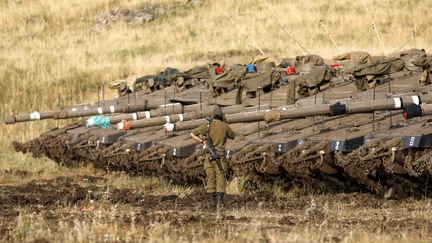 Un soldat israélien devant des véhicules de l'armée israélienne, déployés sur le plateau du Golan, le 10 mai 2018. (MENAHEM KAHANA / AFP)