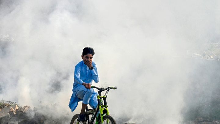 Un enfant à vélo se couvre la bouche pour échapper à la pollution qui touche Lahore, le 1er novembre 2024 au Pakistan. (ARIF ALI / AFP)